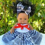 Poupée Madin Dolls en jupe traditionnelle noire à carreaux, haut blanc smocké et nœud assorti fait main en Martinique.
